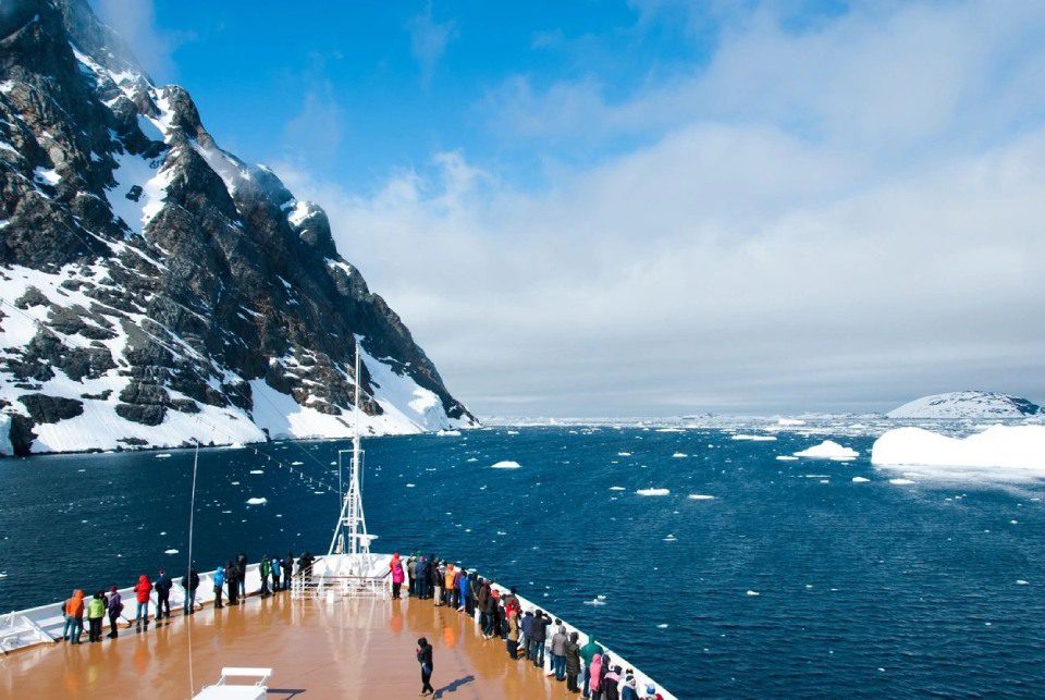 A group of people standing on the deck of a boat.